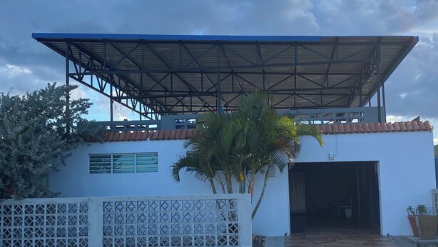 Un bâtiment doté d’une entrée couverte, d’un toit en tuiles et d’une clôture décorative.