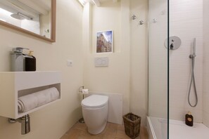 Ein modernes Badezimmer mit Toilette, Dusche, Handtuchhalter und einem Bild an der Wand.