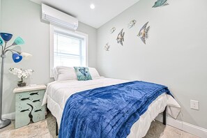 Ein Schlafzimmer mit einem Bett, einem Nachttisch, einer Lampe und Wandbildern.