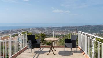Una terraza con dos sillas y una mesa, con vista a un paisaje costero.