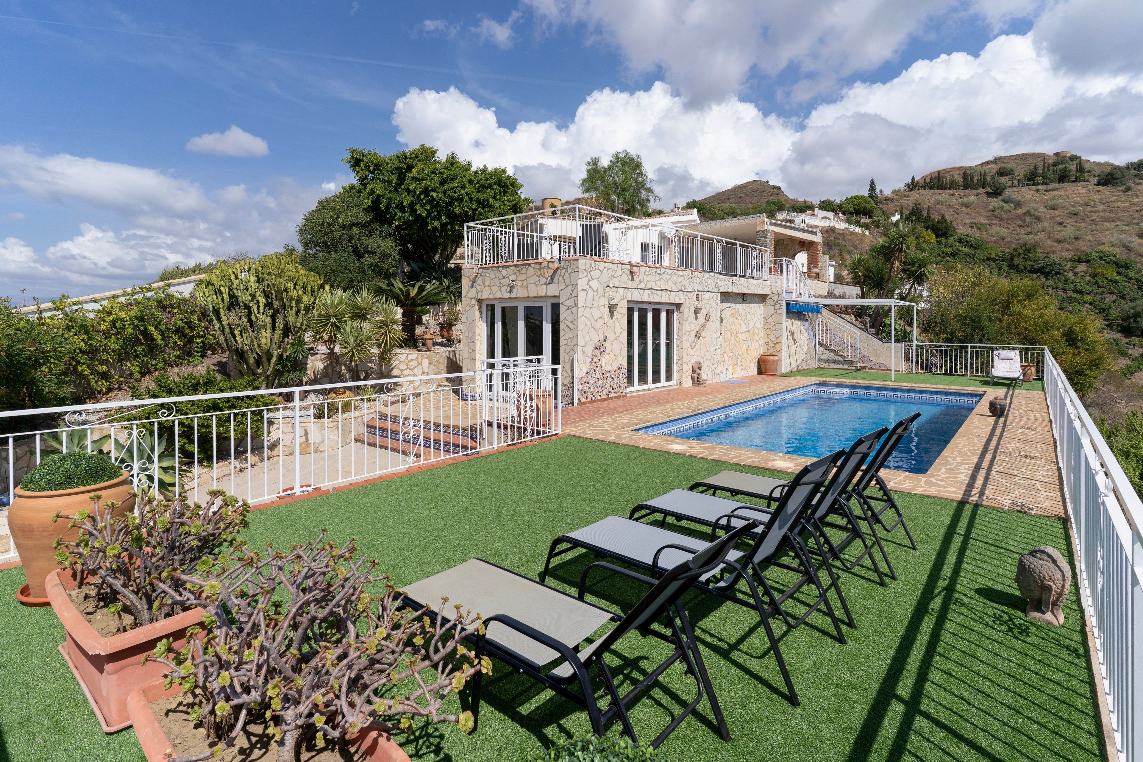 A pool area with artificial grass, a pool, and a white railing.