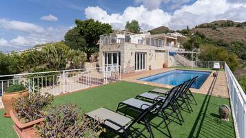 A pool area with artificial grass, a pool, and a white railing.