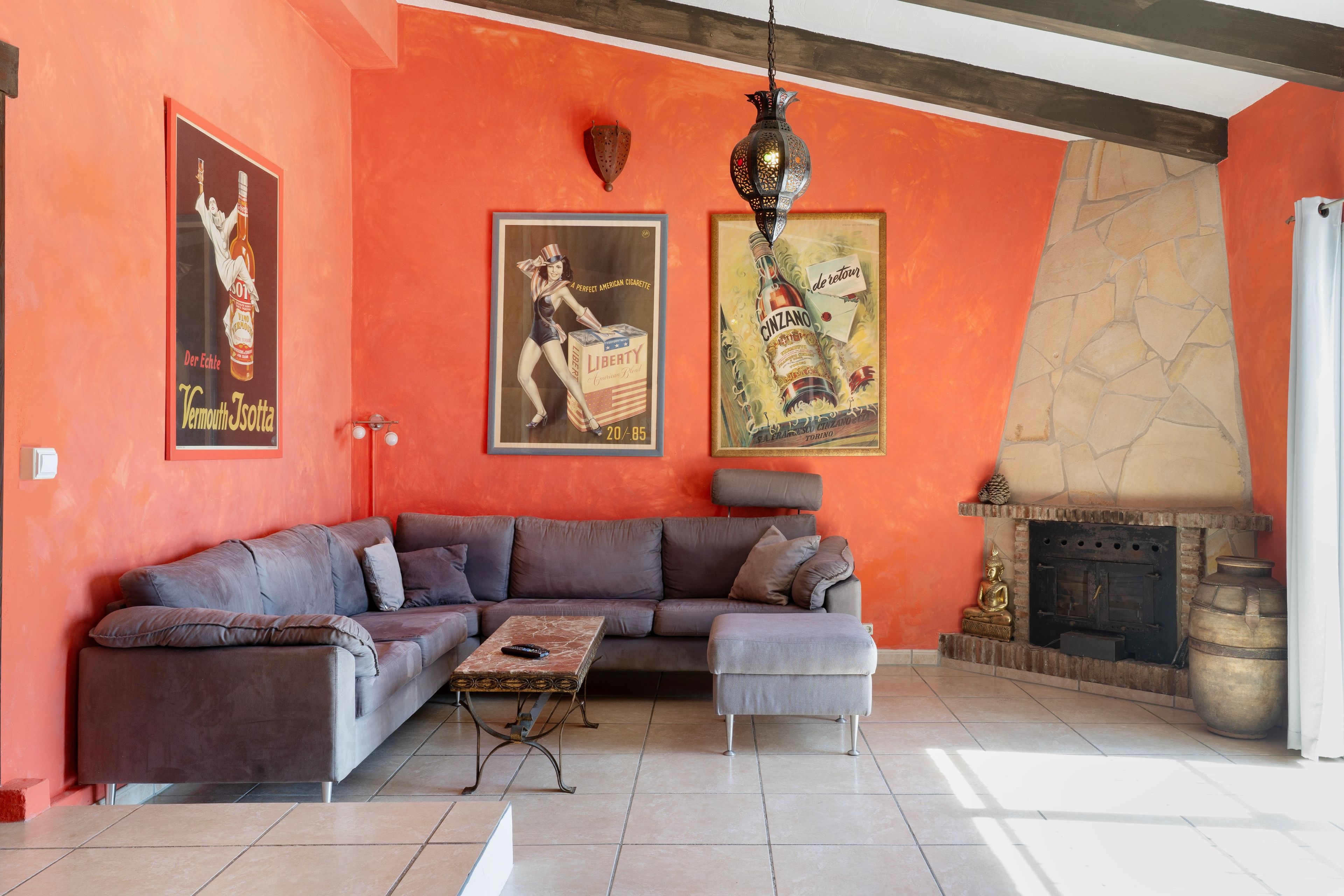 Una sala de estar con un sofá modular, una chimenea y carteles antiguos en la pared.