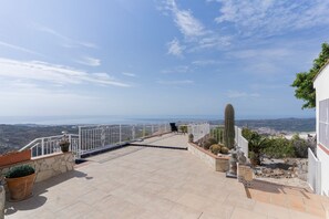 Eine Dachterrasse mit Blick auf das Meer, einem Kaktus und einer Statue.