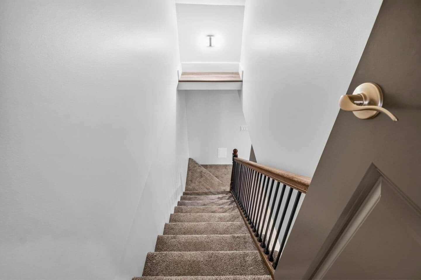 Un escalier avec une rampe en bois et une porte dotée d’une poignée ronde.