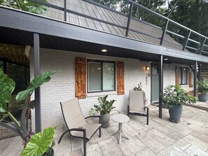 A patio area with a white brick wall, wooden shutters, and potted plants. - Sanctuary - A Cozy Peaceful Cottage Getaway (Knox County)