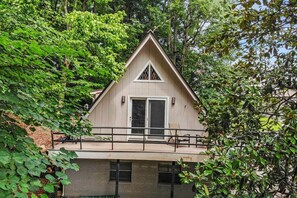 A two-story house with a balcony, surrounded by dense foliage. - Sanctuary - A Cozy Peaceful Cottage Getaway (Knox County)