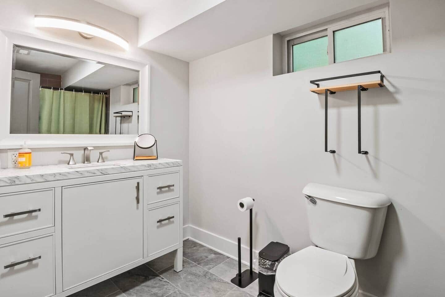 A modern bathroom with a toilet, a sink with a mirror, and a shower area.