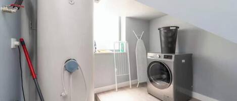 Uma lavanderia compacta com máquina de lavar Bosch, aquecedor de água e varal.