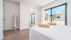 Een slaapkamer met een bed, een spiegel en een glazen schuifdeur naar een buitengebied.