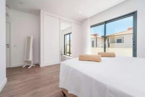 A bedroom with a bed, a mirror, and a sliding glass door leading to an outdoor area. - Villa with a private pool, 2 suites, a barbecue, and air conditioning (Albufeira)
