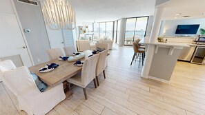 Een moderne eethoek met een houten tafel voor vier personen, omringd door witte stoelen met bekleding.
