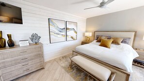 A bedroom with a bed, bedside tables, a dresser, artwork, and a ceiling fan. - Gorgeous Inside and Views in East Pass Towers 602 (Destin)