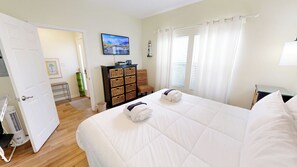 Ein Hotelzimmer mit zwei Betten, einem Fernseher, einer Lampe und einem Fenster mit Vorhängen.
