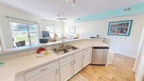 A modern kitchen with a dishwasher, a window with a view, and a ceiling fan. - Perfect Location and Amenities Sandpiper Cove 9126 (Destin)