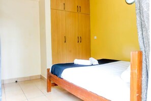 Une pièce avec un lit, une armoire en bois et un mur jaune.
