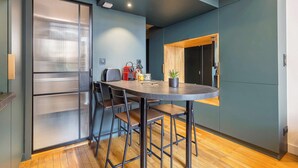 A modern kitchen with a round table, bar stools, and a wooden ceiling. - Pradel - Furnished apartment - Downtown Lyon (Lyon)