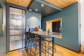 A modern kitchen with a round table, bar stools, and a wooden ceiling. - Pradel - Furnished apartment - Downtown Lyon (Lyon)