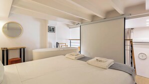 A modern bedroom with a large bed, a bedside table, a mirror, and a view of a balcony. - Pradel - Furnished apartment - Downtown Lyon (Lyon)