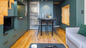 A modern living space with a dining area, a sofa, a TV, and a staircase. - Pradel - Furnished apartment - Downtown Lyon (Lyon)