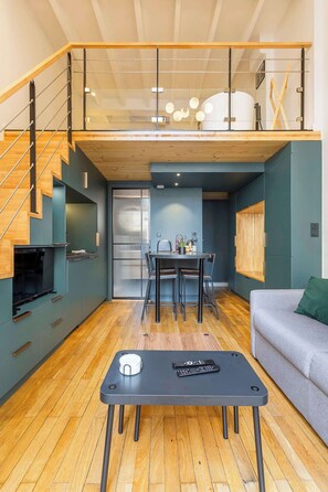 A modern living space with a dining area, a sofa, a TV, and a staircase. - Pradel - Furnished apartment - Downtown Lyon (Lyon)