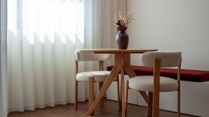 A room with a wooden table and two chairs, a vase with dried plants, and a red bench against a white wall. - Elegant 1BR Retreat near Metro by LovelyStay (Vila Nova de Gaia)