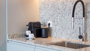 A kitchen with a granite countertop, a coffee maker, a kettle, and a sink. - Elegant 1BR Retreat near Metro by LovelyStay (Vila Nova de Gaia)