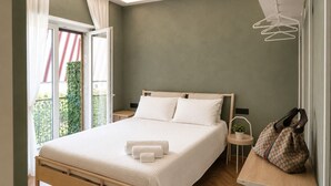 Una camera da letto con un letto, comodini, una lampada a sospensione, una finestra con tende e vista su del verde all'esterno.