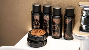 Un bagno con un lavandino, uno specchio e quattro flaconi di prodotti MYA Argan.