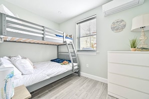 A bunk bed with a ladder, a dresser, a window with blinds, and a wall-mounted air conditioner. - Seaside Serenity: Salty Shore Retreat (Wildwood)