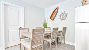 Ein Essbereich mit einem Holztisch und Stühlen, einer Topfpflanze sowie Wanddekoration im maritimen Stil.