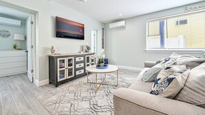 Ein modernes Wohnzimmer mit einer Couch, einem Couchtisch und einem an der Wand befestigten Fernseher.