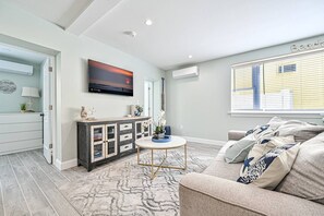 A modern living room with a sofa, a coffee table, and a TV mounted on the wall. - Seaside Serenity: Salty Shore Retreat (Wildwood)