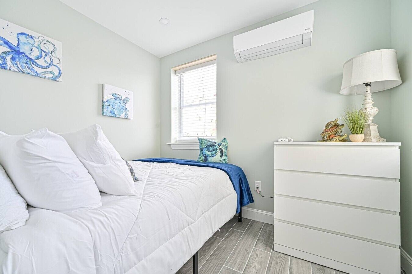 Quarto com cama, penteadeira, janela com persianas e decoração na parede.