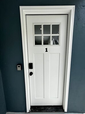 A white door with a number '1' above it, a small window, and a doorbell. - Seaside Serenity: Salty Shore Retreat (Wildwood)