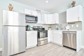 A modern kitchen with stainless steel appliances, white cabinetry, and a tiled backsplash. - Seaside Serenity: Salty Shore Retreat (Wildwood)