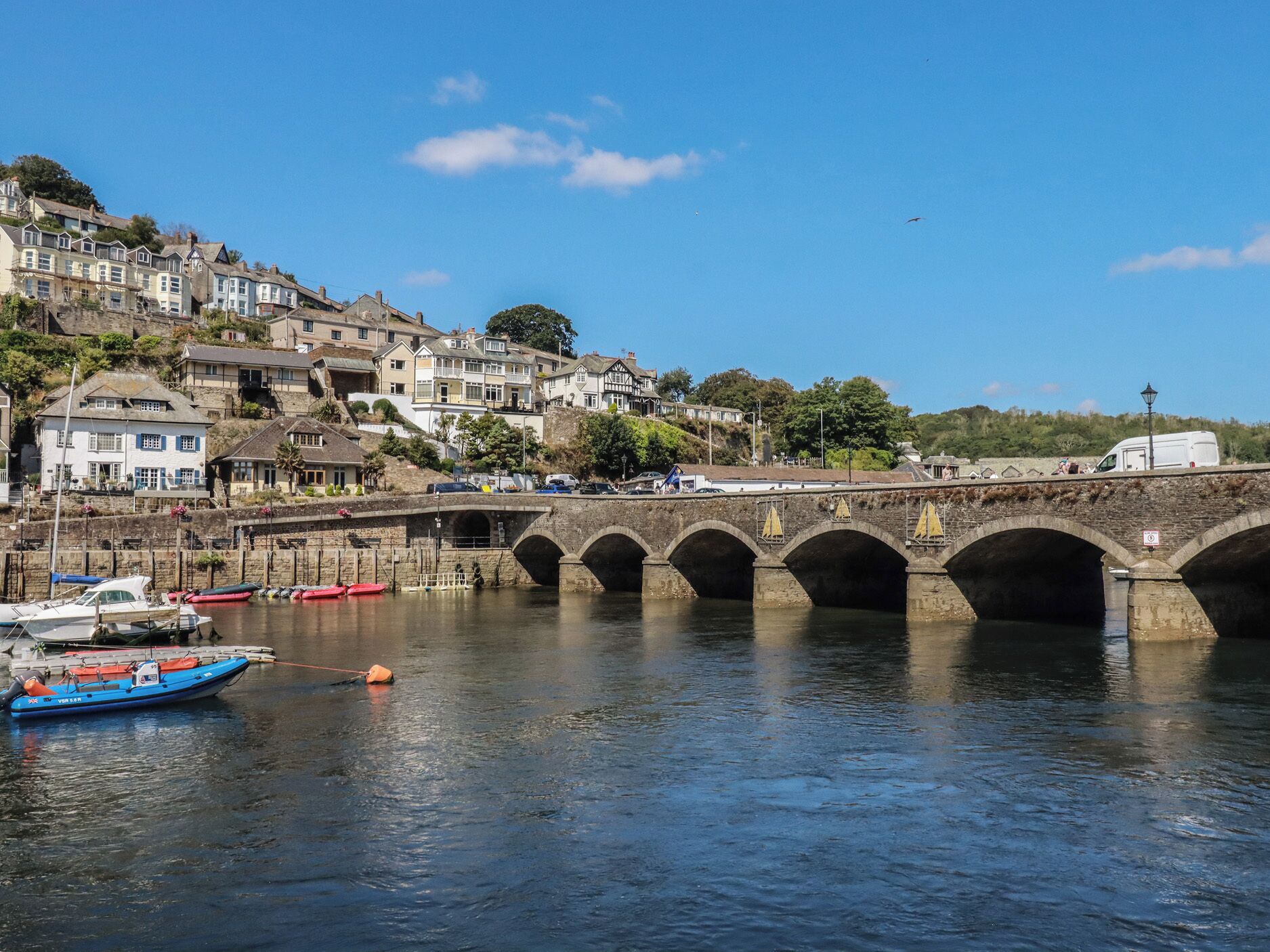 A stone bridge over a river with boats docked nearby.