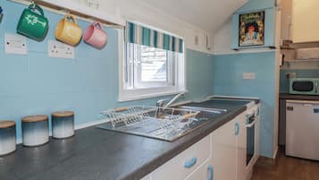 A kitchen with a sink, a dish rack, and a microwave.
