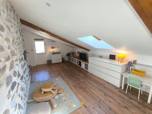 A spacious attic room with a sloped ceiling, wooden flooring, a large window, and a skylight. - Fajureya House (Vaumeilh)