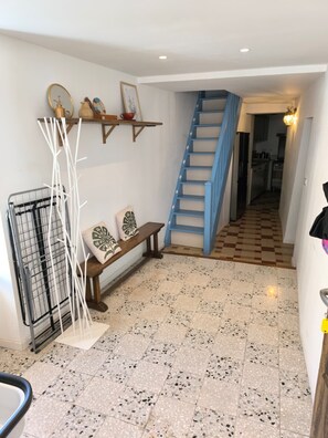 A hallway with a checkered floor, a blue staircase, a metal rack, and a bench with cushions. - Fajureya House (Vaumeilh)
