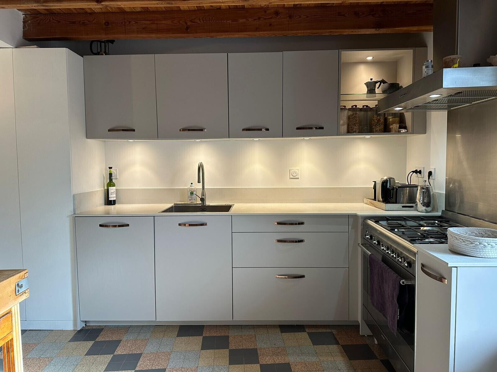 Een moderne keuken met witte kasten, een roestvrijstalen spoelbak en een gasfornuis.