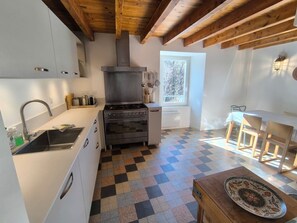 Eine kompakte Küche mit Herd, Backofen und Spüle, ein Essbereich mit Tisch und Stühlen sowie ein Fenster für natürliches Licht.