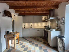 Eine kleine Küche mit weißen Schränken, einem Holztisch und einem gemusterten Boden.