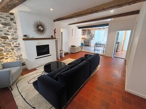 Ein Wohnzimmer mit Kamin, einer Couch und einem Essbereich im Hintergrund.
