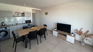 A modern kitchen with a dining area, a flat-screen TV, and a small plant. - Atmosphere and Ocean View (Sainte-Anne)
