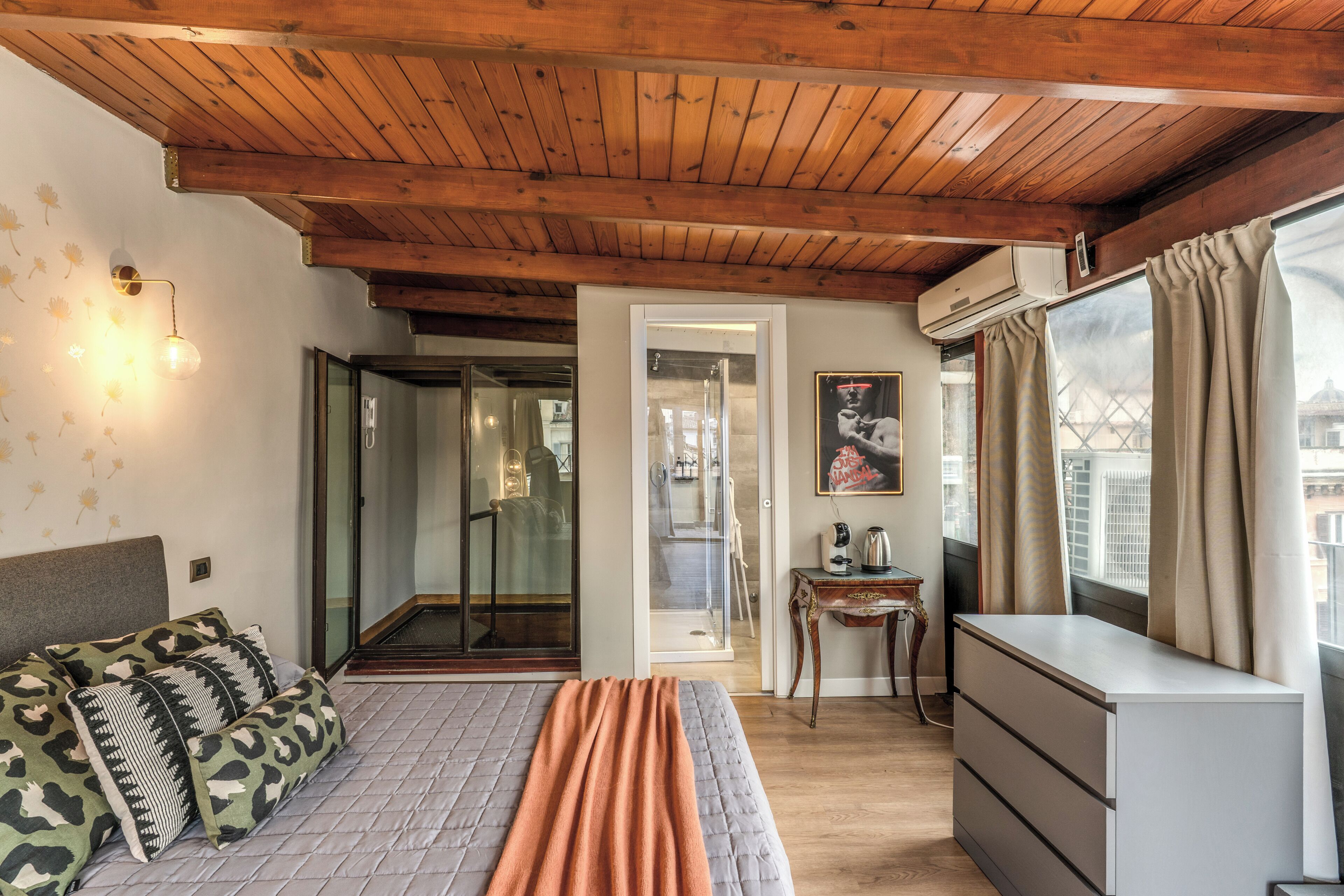 Een slaapkamer met een bed, een kast, een spiegel en een raam met gordijnen.