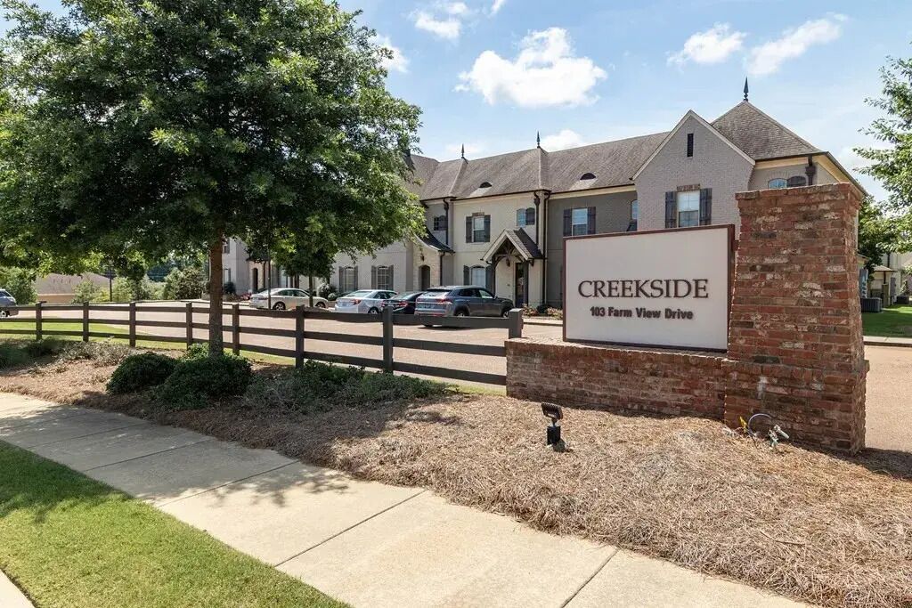 A residential building with a sign indicating 'CREEKSIDE 103 Farm View Drive.'