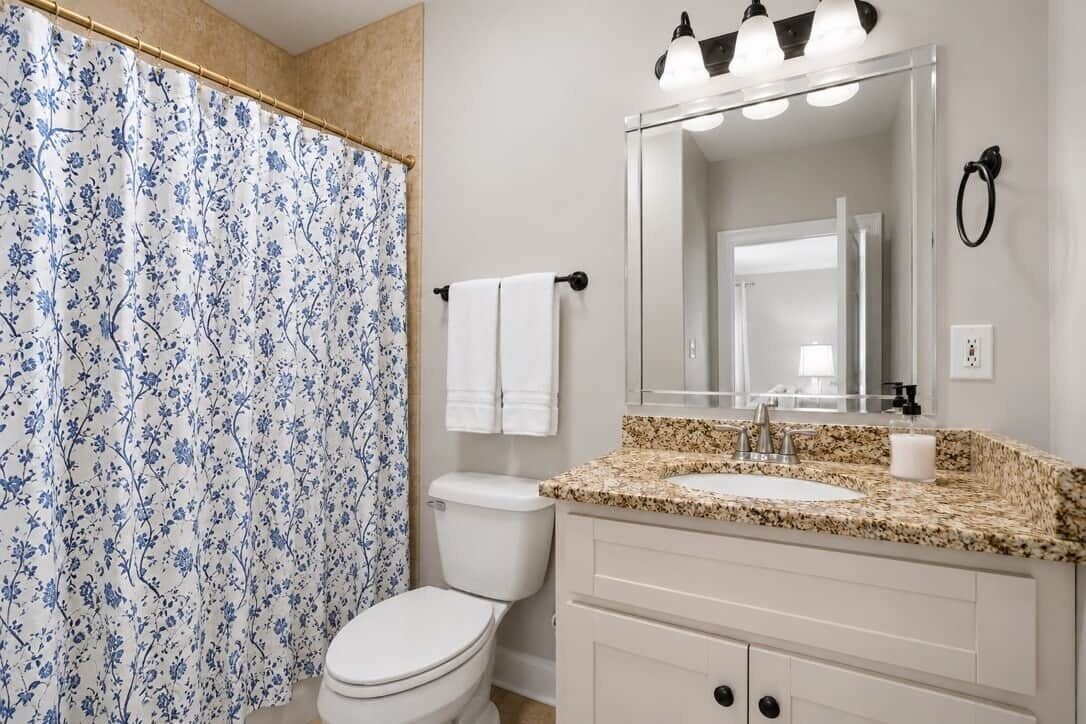 A bathroom with a toilet, sink, and shower curtain.