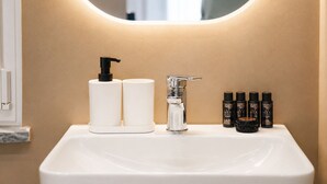 Un lavamanos de baño con un grifo moderno, un dispensador de jabón y un juego de artículos de tocador.