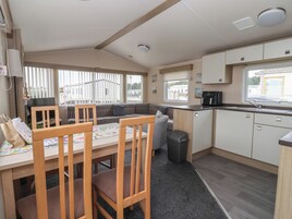 A compact kitchen with a dining area, a sofa, and a trash bin.